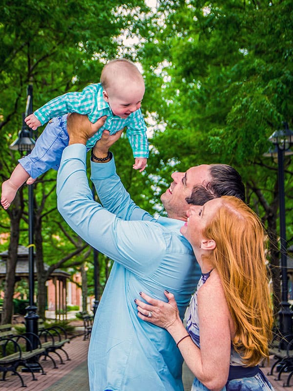 Red-headed mother laughs at father and baby in blue